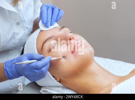 Procedure for cleaning the skin of the face with a steel appliance with a spoon from blackheads and acne. Stock Photo