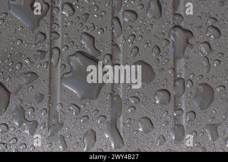 Close up of the texture of rainwater, raindrops on a gray rough plastic chair. Pattern Stock Photo
