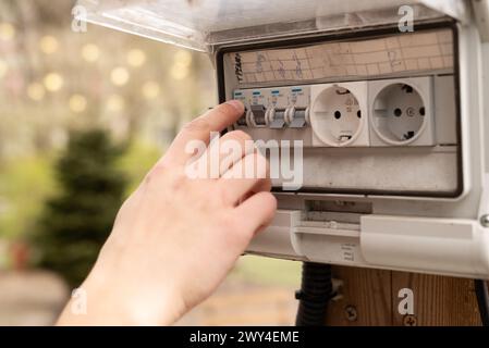 Man's finger checking an electricity in the fuse box outdoor. Block of sockets with a switch at the garden . High quality photo Stock Photo