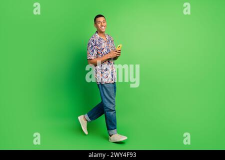 Photo of cheerful attractive man addicted user wear trendy clothes hold phone walk gps navigation isolated on green color background Stock Photo