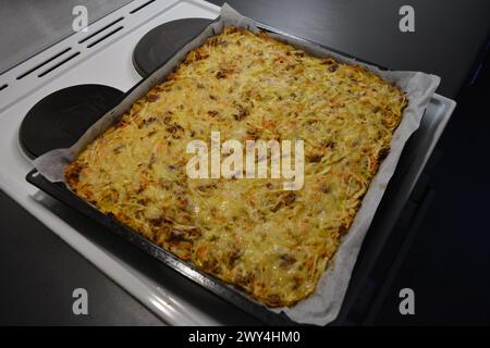 Cuisine, cooking, delicious vegetable casserole made of chopped cabbage, mushrooms, white onion, minced meat sprinkled with cheese. Stock Photo