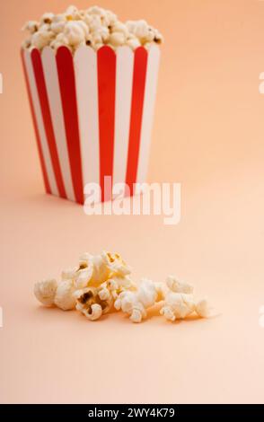 A striped popcorn bucket on a tan background. Stock Photo