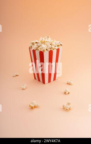 A striped popcorn bucket on a tan background. Stock Photo