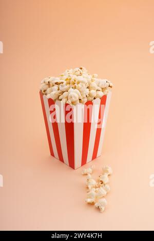 A striped popcorn bucket on a tan background. Stock Photo