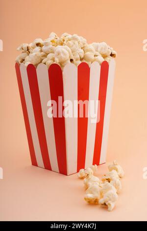 A striped popcorn bucket on a tan background. Stock Photo