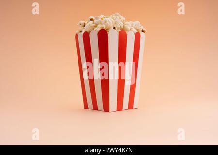 A striped popcorn bucket on a tan background. Stock Photo