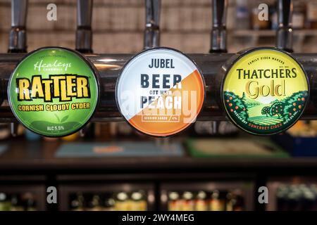 Beer Cider pump clips badges Rattler Cider Jebel Beer Thatchers Gold on a beer engine in a pub in Newquay in Cornwall in the UK. Stock Photo