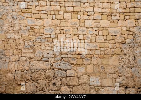 Old limestone wall irregular bricks stones textured background. Stock Photo