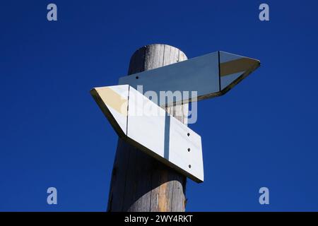 Wooden signpost with two arrows and clear sky Stock Photo