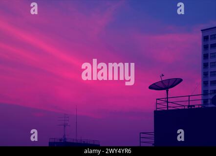 Pop Art of Vibrant Blue and Purple Tone Satellite Dish on the High Building Against Evening Sky Stock Photo