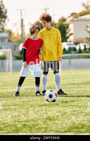 Two young men stand confidently on top of the soccer field, surveying the landscape below them. The vibrant green grass complements their energetic po Stock Photo