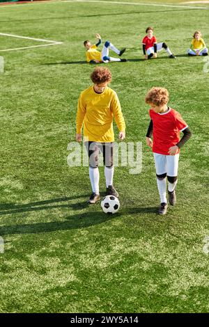 A vibrant scene of a group of children immersed in a game of soccer on a green field. They energetically kick the ball, run, and chase each other, sho Stock Photo