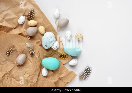 Easter eggs and feathers on a brown kraft paper background on a white table. Top view. For easter greeting cards with copy space. Stock Photo