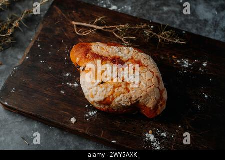 a colomba pasquale, a typical italian easter bread, on a wooden cutting board, placed on a dark rustic table Stock Photo