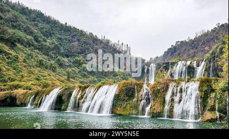 The Jiulong waterfall and river in lush mountain landscape with valley in the background Stock Photo