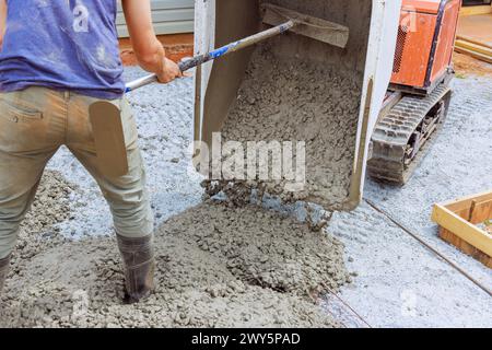 Pouring fresh cement from concrete buggy into framework in ground during construction Stock Photo