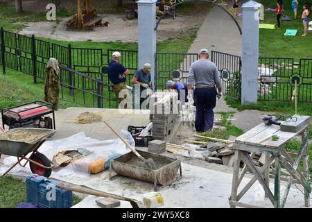 A group of builders in a city park are repairing a stone staircase. Stock Photo