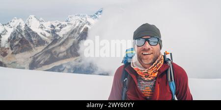 Cheerful laughing climber in sunglasses portrait with backpack ascending Mera peak high slopes at 6000m enjoying legendary Mount Everest, Nuptse, Lhot Stock Photo