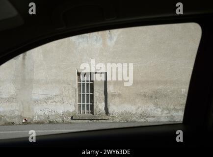window with bars and concrete wall seen through a car window Stock Photo