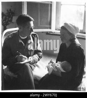 CHRISTENING BABIES IN BELSEN CAMP - The padre talks to Raissa Aspa [?] of Woroschilowgrad after christening her five day old child. , British Army, 21st Army Group Stock Photo