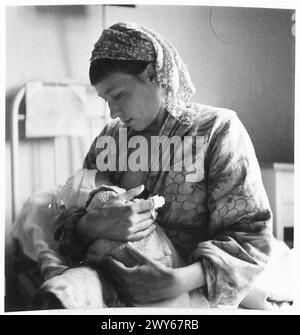 CHRISTENING BABIES IN BELSEN CAMP - Helena Kwartowaja of Rostov [Russia] also feeds her child. , British Army, 21st Army Group Stock Photo