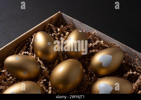 Gold eggs in paper box on black background. Stock Photo
