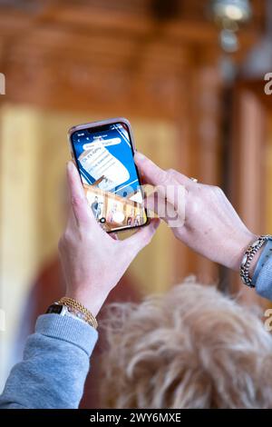 Paphos Cyprus. A tourist uses the Google translate App on her mobile phone to translate Greek text, on a church ceiling, into English text Stock Photo
