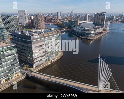 Drone photo low down over the Manchester Ship Canal with the Media City Footbridge & BBC Studios in the foreground with MediaCityUK & Salford Quays Stock Photo