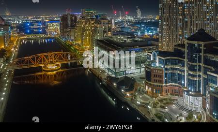 Night time drone photography of Eerie & Huron Basin in Salford Quays looking down past The Vic, BUPA, Detroit Bridge, NV Buildings & X1 to MediaCityUK Stock Photo