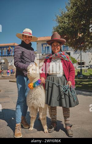 Cusco, Peru - March 2024. Ladies from Cusco pose with their llamas and alpacas and tourist for the photo, near the plaza. Cusco, Peru. Stock Photo