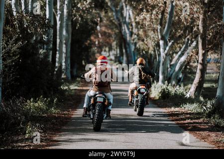 Two bikers riding through a forest on a narrow trail Stock Photo