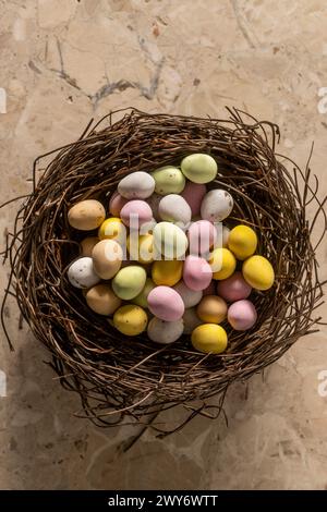 Plan view shot of colourful sugar coated mini eggs arranged in a faux bird's nest. Stock Photo