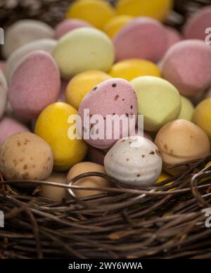 Close-up of colourful sugar-coated chocolate mini eggs arranged in a faux bird's nest. Stock Photo