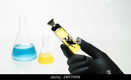 bird flu vaccination illustration showing liquid in a glass vial with a black bird silhouette on the bottle and full flasks with blue and yellow liqui Stock Photo