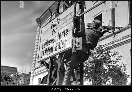 WW2 USSR/Nazi Germany KHARKOV 1943 Red Army soldier destroys a Nazi German sign on Dzerzhinsky Square in liberated Kharkov. During the German occupation from 1942 it was called “German Army Square”. From the end of March to August 23, 1943, it was called “Leibstandarte SS Square” after the name of the 1st SS Panzer Division “Leibstandarte SS Adolf Hitler” that captured the city for the second time in the third battle for Kharkov. Kharkiv also known as Kharkov the second-largest city in Ukraine Stock Photo