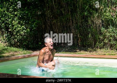 A man is diving into a swimming pool in the summer season Stock Photo