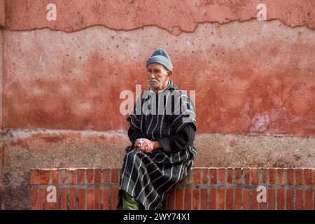 A man seated on a brick bench by graffiti wall Stock Photo