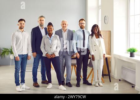 Group of confident business people standing at office looking at the camera and smiling. Stock Photo