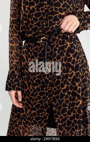 Model flaunts trendy giraffe print shirt dress with black belt. Perfect for casual outings or a night out. Stock Photo