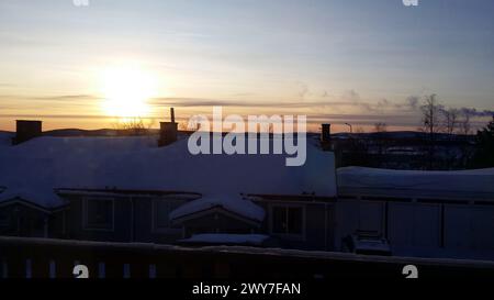 Sunrise in a small snowy town in the north of Sweden. The sun is rising over the rooftops. Stock Photo