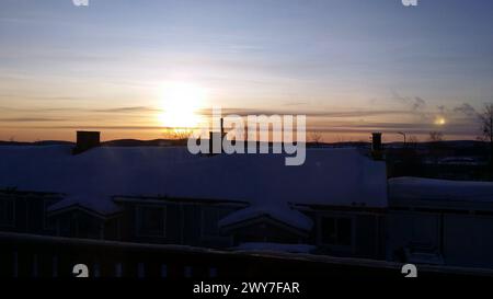 Sunrise in a small snowy town in the north of Sweden. The sun is rising over the rooftops. Stock Photo