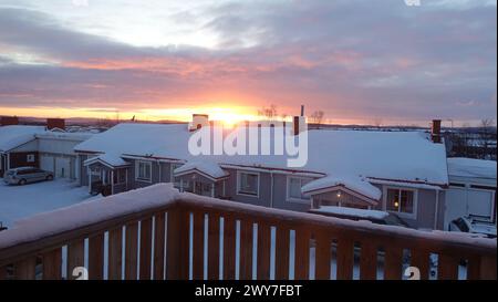 Sunrise in a small snowy town in the north of Sweden. The sun is rising over the rooftops. Stock Photo