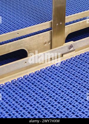 A close-up of a blue polyurethane belt in modular industrial conveyor system. Stainless steel transport systems in industrial factories. Stock Photo