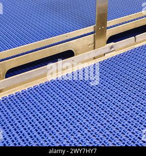 A close-up of a blue polyurethane belt in modular industrial conveyor system. Stainless steel transport systems in industrial factories. Stock Photo