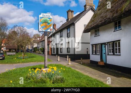 Low Street, Hoxne, Suffolk, East Anglia,  UK. The village sign on the green with spring daffodils. Stock Photo