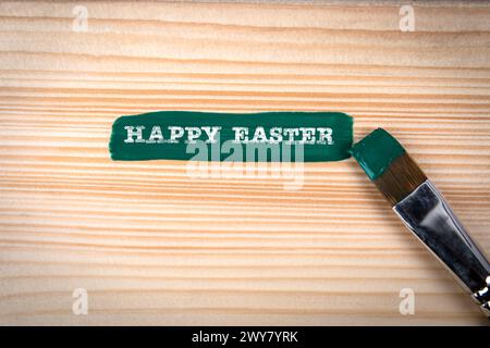 Happy Easter. Green paint and brush on wood texture background. Stock Photo