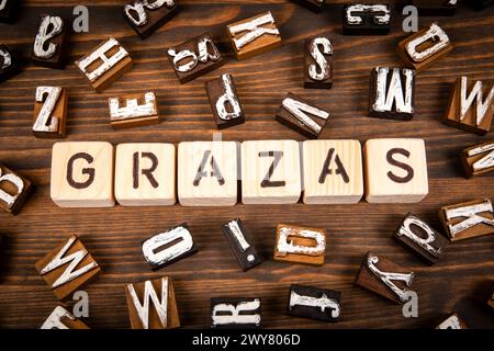 Thank you in Galician. Alphabet blocks on wood texture background. Stock Photo