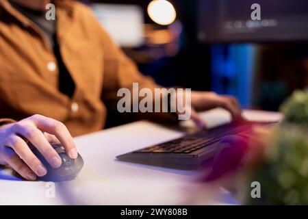 Man doing software quality assurance using keyboard and mouse, reading source code on computer. System administrator inspecting coding on desktop PC, looking to fix potential issues, close up shot Stock Photo