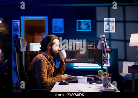 Man drinking coffee while doing software quality assurance, reading source code on computer. Developer inspecting coding on desktop PC and enjoying hot beverage, looking to fix potential issues Stock Photo