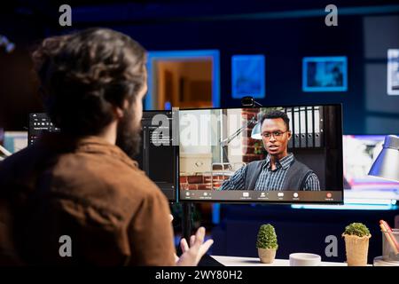 IT specialist working from home in videocall with coworker, testing and deploying programs and systems. Programmer checking code with colleague in teleconference, sitting at desk chair in apartment Stock Photo